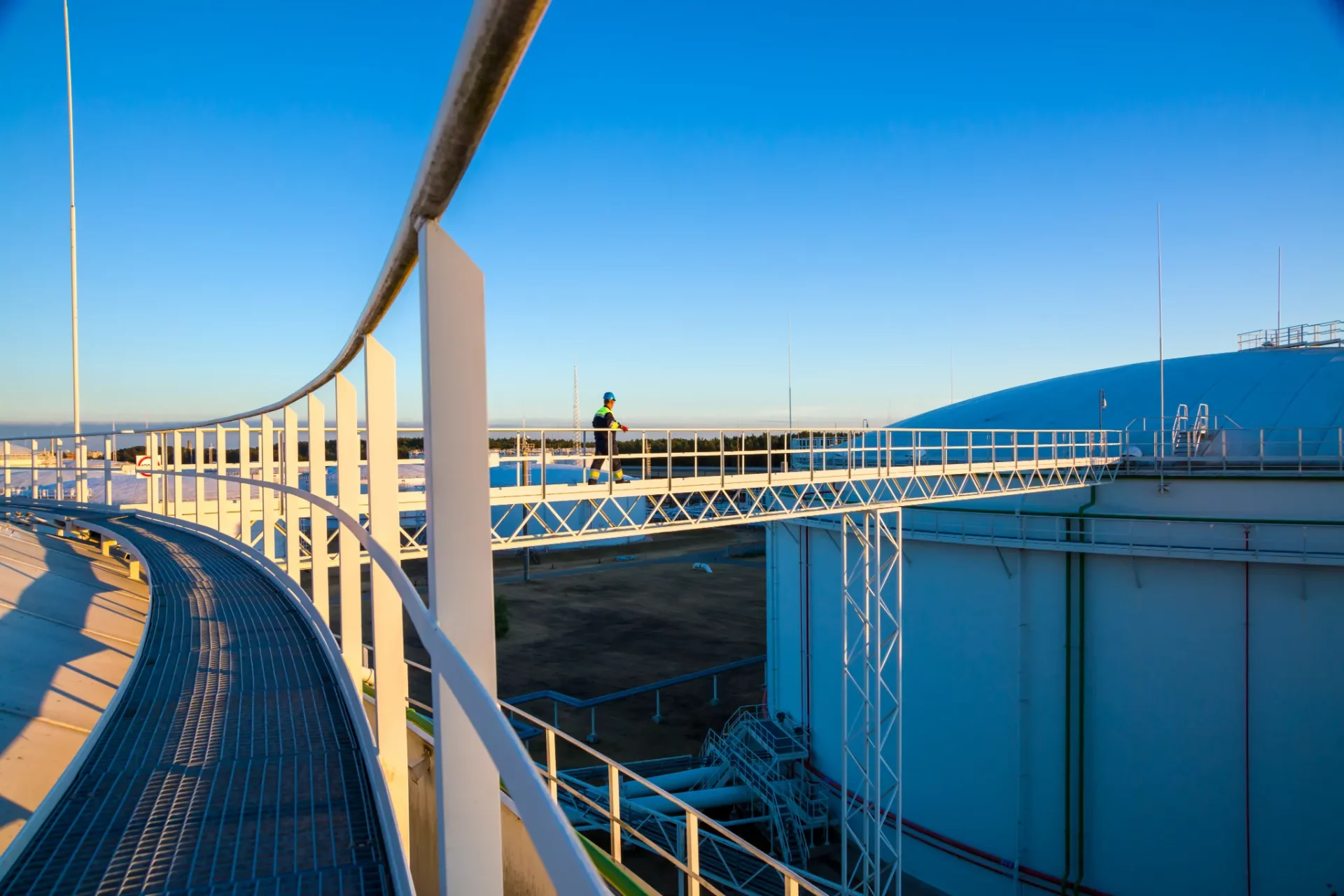 terminal operator walking between tank roofs at sunset